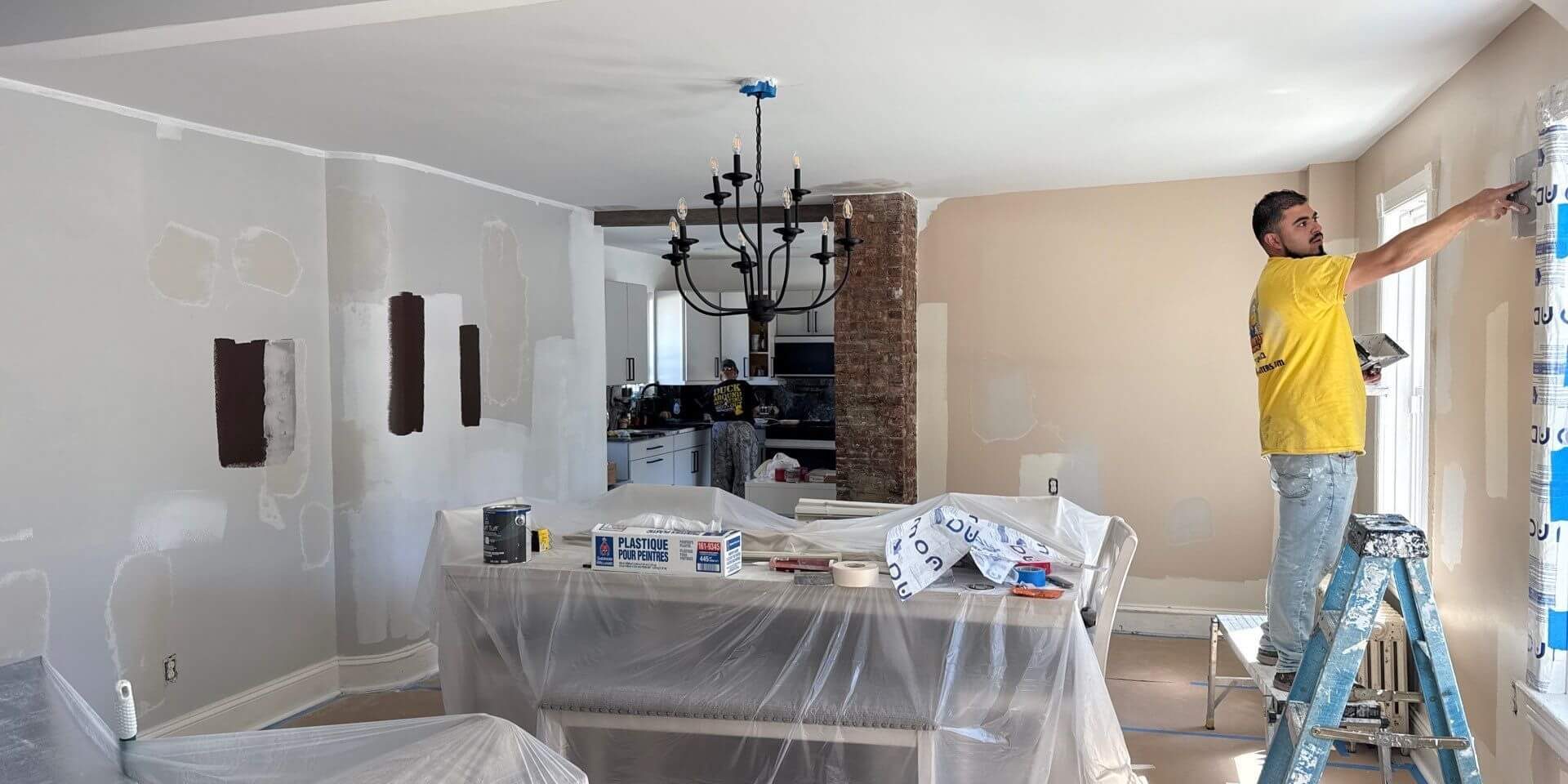 sunny day painting co team member on ladder prepping a wall for painting in levittown pa